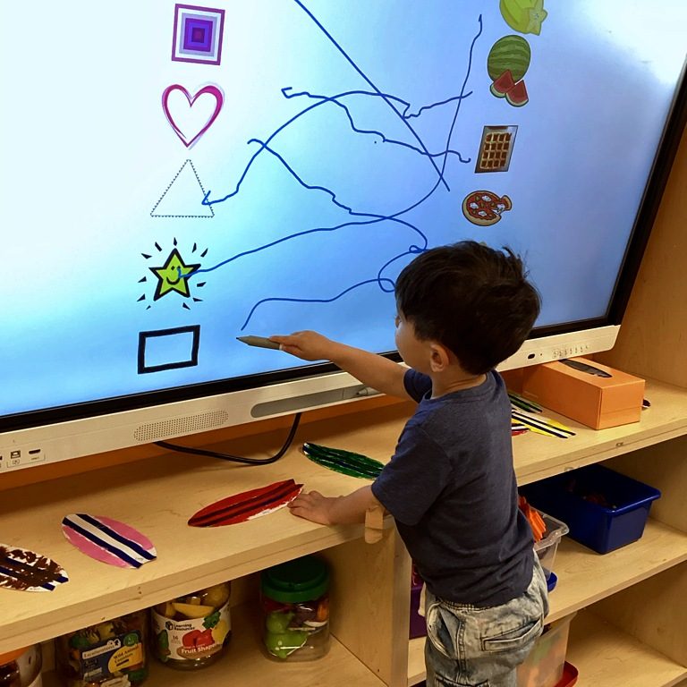 A child matching shapes on an interactive smartboard