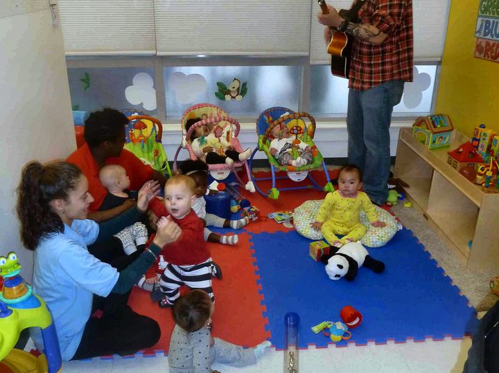 An adult playing guitar with infants during a music enrichment class