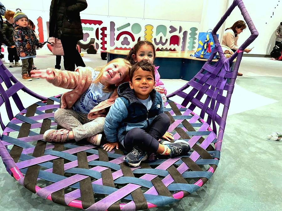 Children playing together on a woven basket swing