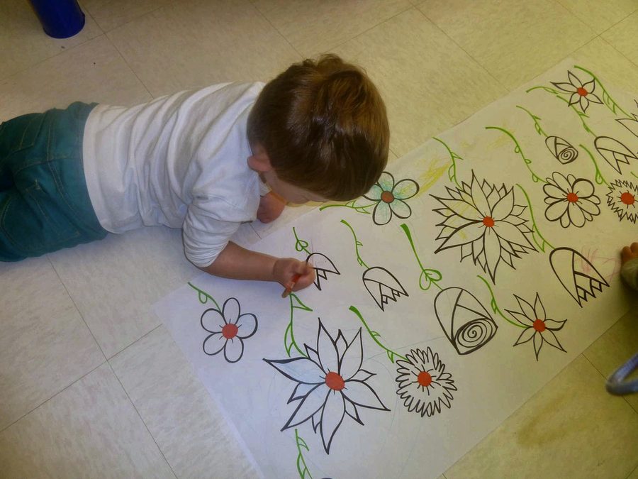 A child coloring a large floral mural in the Gooseberry room