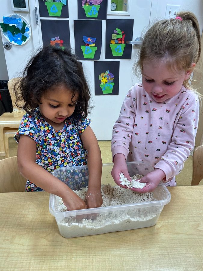 Two children sharing a rice sensory bin